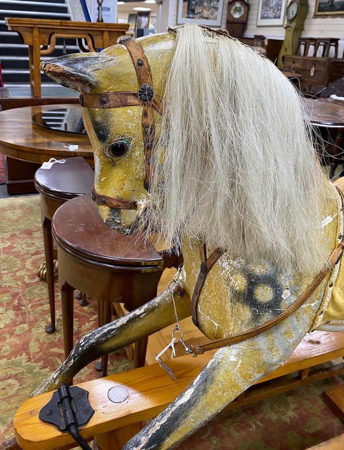 An early 20th century Ayers type dapple rocking horse with tan leather tack on pine safety frame, length 145cm, height 124cm